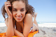 Young woman lying down while showing a great smile with her hand Young woman lying down while showing a great smile with her hand