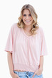 A woman with her arms in her pocket is smiling at the camera
