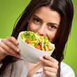 portrait of young woman holding a fresh salad over green portrait of young woman holding a fresh salad over green