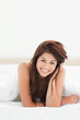 Photo: A woman lying at the end of the bed smiling, with her head tilte A woman lying at the end of the bed smiling, with her head tilte