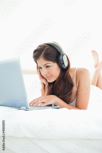 Foto: Woman listening to her headphones and watching her laptop, with Woman listening to her headphones and watching her laptop, with