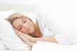 Foto: Woman sleeping in bed, hands positioned beside her face Woman sleeping in bed, hands positioned beside her face