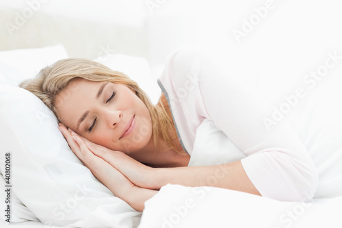 Foto: Woman sleeping in bed, hands positioned beside her face Woman sleeping in bed, hands positioned beside her face