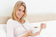 Woman in bed with a bowl of cereal in hand and a slightly raised