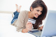 Photo: Woman on her laptop with credit card in hand and smiling Woman on her laptop with credit card in hand and smiling