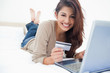 Photo: Woman smiling and looking ahead as she uses her laptop, and cred Woman smiling and looking ahead as she uses her laptop, and cred