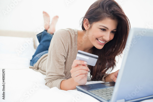 Photo: Woman on her laptop with credit card in hand and smiling Woman on her laptop with credit card in hand and smiling