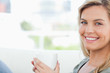 Woman smiling, looking forward and holding up a mug in hands