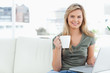 Woman looking forward and smiling as she uses her laptop and hol