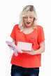 Young blonde woman showing her surprise while opening a present