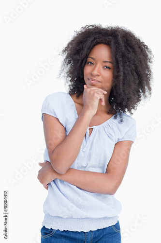 Photo: Young woman standing up with hand on chin and arms crossed Young woman standing up with hand on chin and arms crossed