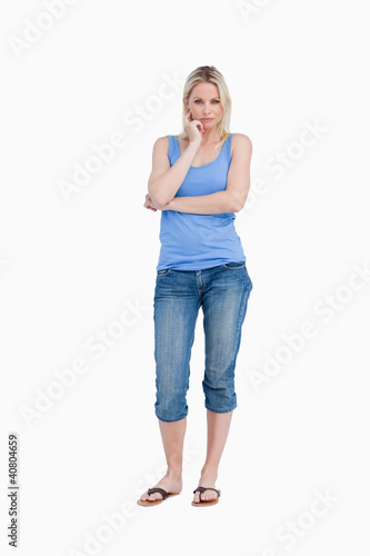 Foto: Serious blonde woman standing up with finger on her cheek Serious blonde woman standing up with finger on her cheek