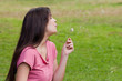 Young relaxed woman blowing a dandelion