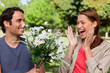 Woman laughing excitedly as she is presented with flowers by her