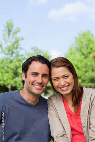 Photo: Two friends smiling as the look ahead while leaning against each Two friends smiling as the look ahead while leaning against each