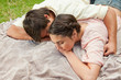 Man with his arm around his friend while lying on a blanket