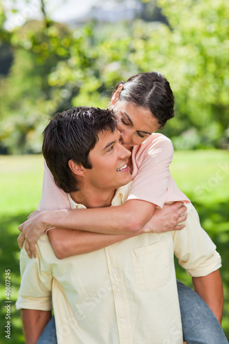 Photo: Man looking at his friend as he is carrying her on his back Man looking at his friend as he is carrying her on his back