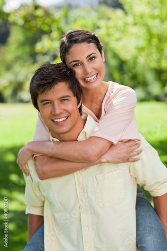 Foto: Woman looking ahead while her friend is carrying her on his back Woman looking ahead while her friend is carrying her on his back
