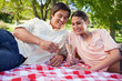 Two friends looking at glasses of champagne during a picnic