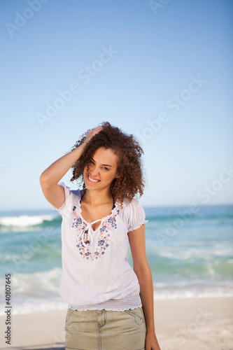 Photo: Young woman standing in front of the sea with hand on her head Young woman standing in front of the sea with hand on her head