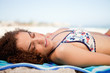 Side view of an attractive woman napping on the beach while turn