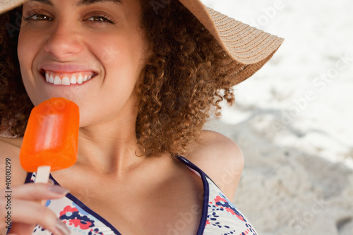 Foto: Young attractive woman going to eat an orange ice lolly on the b Young attractive woman going to eat an orange ice lolly on the b