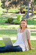 canvas print picture - Smiling woman with her laptop sitting in the park
