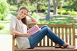 Side view of a smiling woman sitting on a park bench with her bo