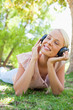 Smiling woman with headphones enjoying music on the lawn