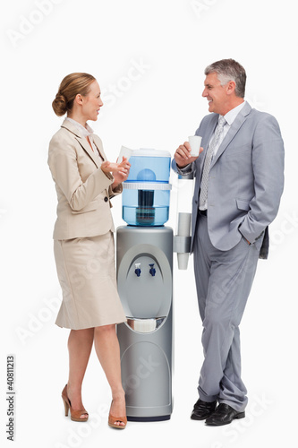 Photo: Business people talking next to the water dispenser Business people talking next to the water dispenser