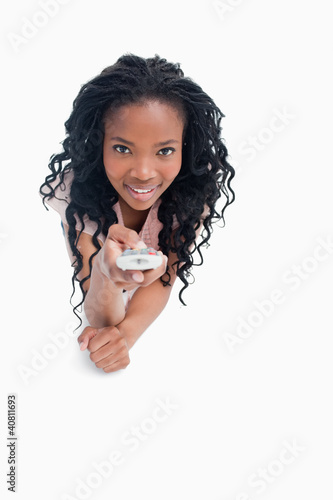 Photo: A smiling young girl is pointing a television remote at the came A smiling young girl is pointing a television remote at the came