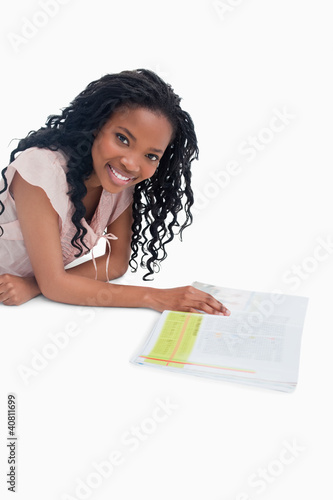 Photo: A smiling woman is lying on the floor with a book in front of he A smiling woman is lying on the floor with a book in front of he