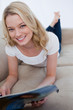Photo: A smiling woman is lying on a couch and holding a magazine A smiling woman is lying on a couch and holding a magazine