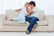 A couple are sitting on a couch looking at each other with their