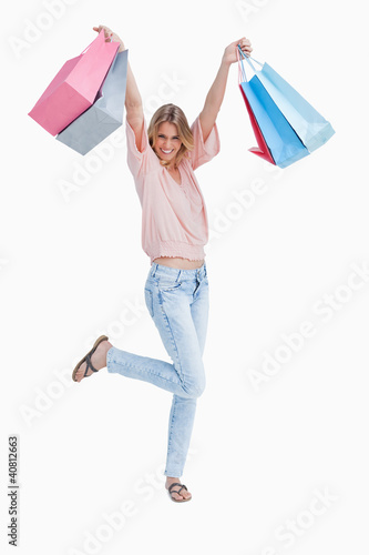 Foto: A woman is standing holding up shopping bags A woman is standing holding up shopping bags