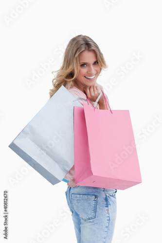 Foto: A woman looking back at the camera is carrying shopping bags ove A woman looking back at the camera is carrying shopping bags ove