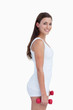 Side view of a smiling woman holding dumbbells