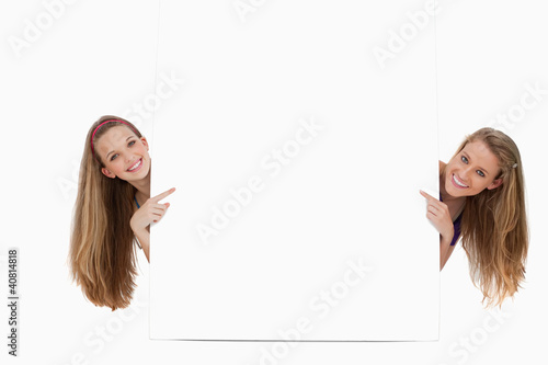 Photo: Portrait of wo long hair women back of a blank sign Portrait of wo long hair women back of a blank sign