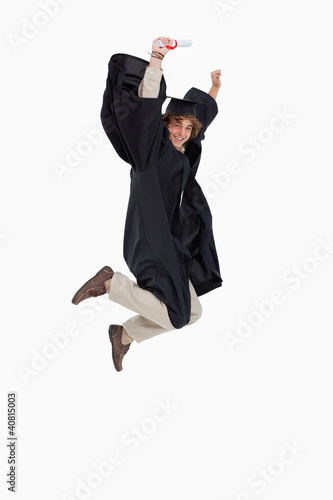 Photo: Happy male student in graduate robe jumping Happy male student in graduate robe jumping