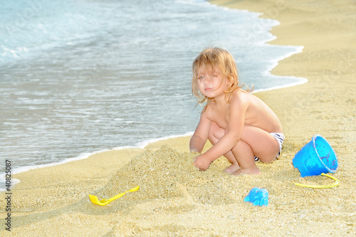 Photo: Happy child on the beach playing with her toys Happy child on the beach playing with her toys