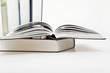 pile of books with one book open on white background