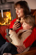Mother And Daughter Relaxing With Hot Drink Watching TV By Cosy
