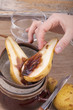 hand holding fresh halved pear with melted chocolate