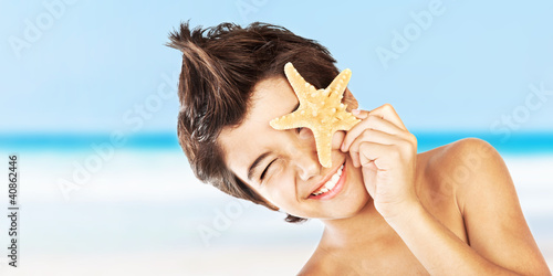 Photo: Happy face boy with starfish on the beach Happy face boy with starfish on the beach