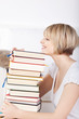 blonde frau mit einem stapel bücher