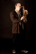 Foto: Jazzman playing saxophone with eyes closed on dark background Jazzman playing saxophone with eyes closed on dark background