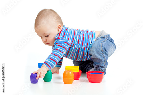 Photo: baby playing with colurful cup toys on floor, isolated over whit baby playing with colurful cup toys on floor, isolated over whit