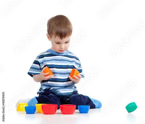 Photo: Funny little child is playing with toys while sitting on floor, Funny little child is playing with toys while sitting on floor,