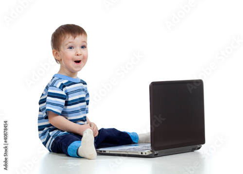 Photo: Cheerful child boy using a laptop over white background Cheerful child boy using a laptop over white background