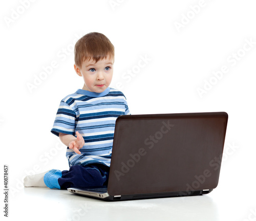 Photo: Cheerful child boy using a laptop over white background Cheerful child boy using a laptop over white background
